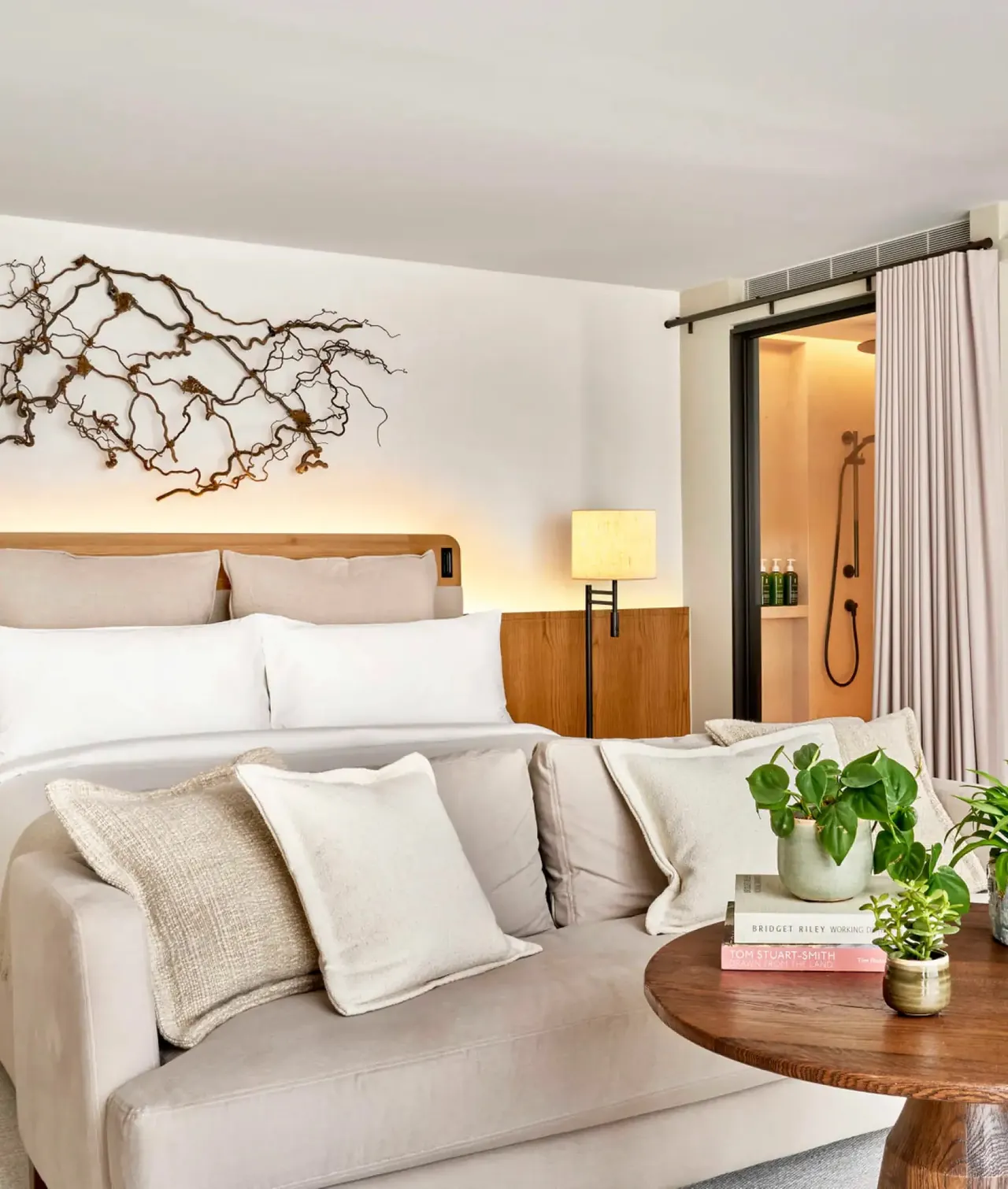 A studio suite with a branch artwork above the bed and a sofa.