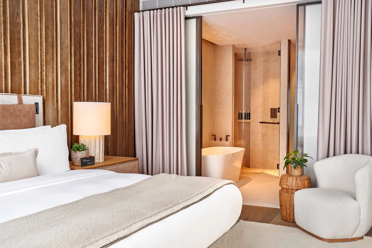 A guest room with an open view into the bathroom and its freestanding tub.
