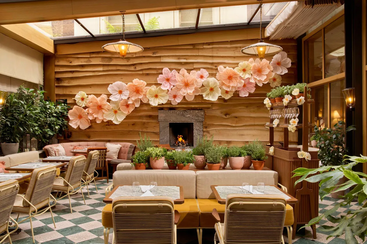 A plant-filled dining room with a timber wall and a large floral display.