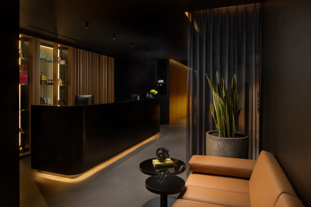 The dimly lit spa reception with dark wood and plants.