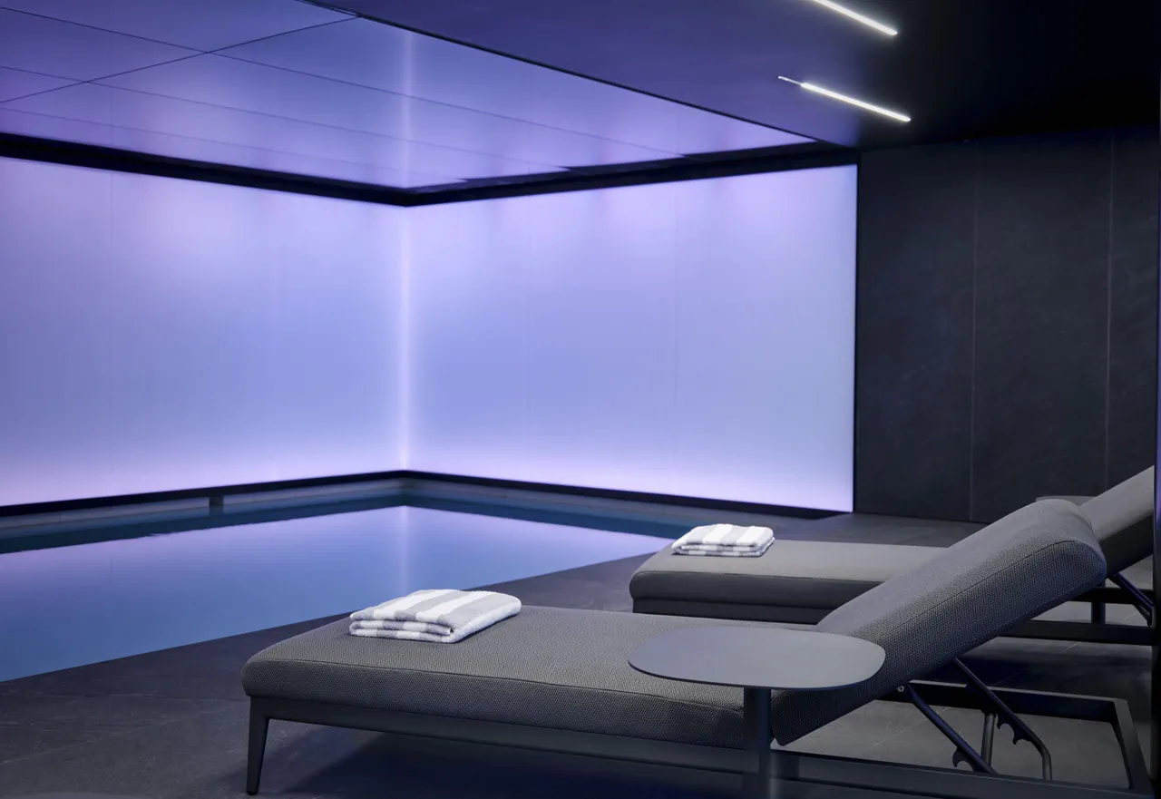 Sun loungers lined up beside the softly lit indoor pool.