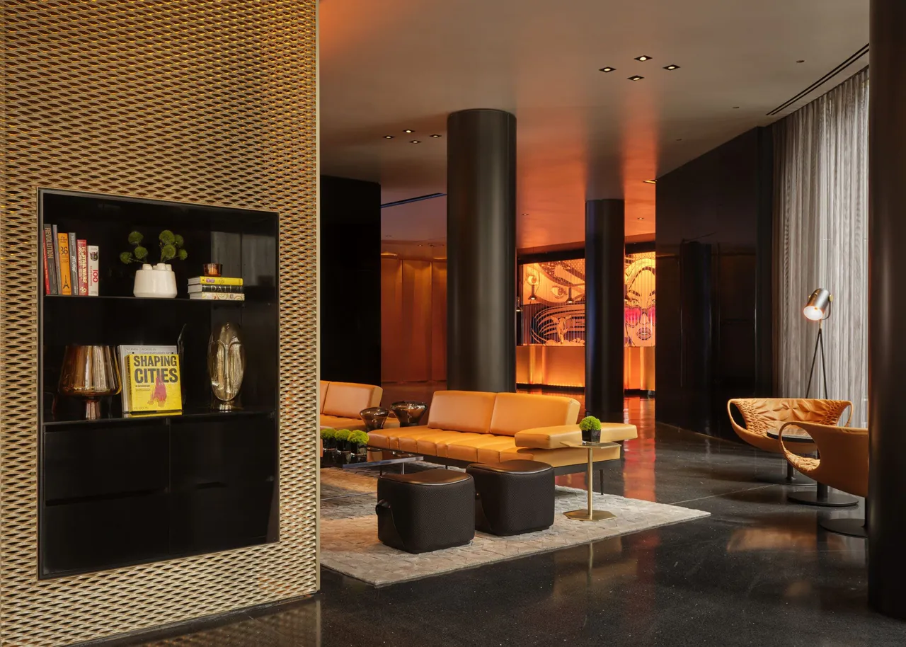 A lobby corner with bookshelves and orange sofas under low amber light.