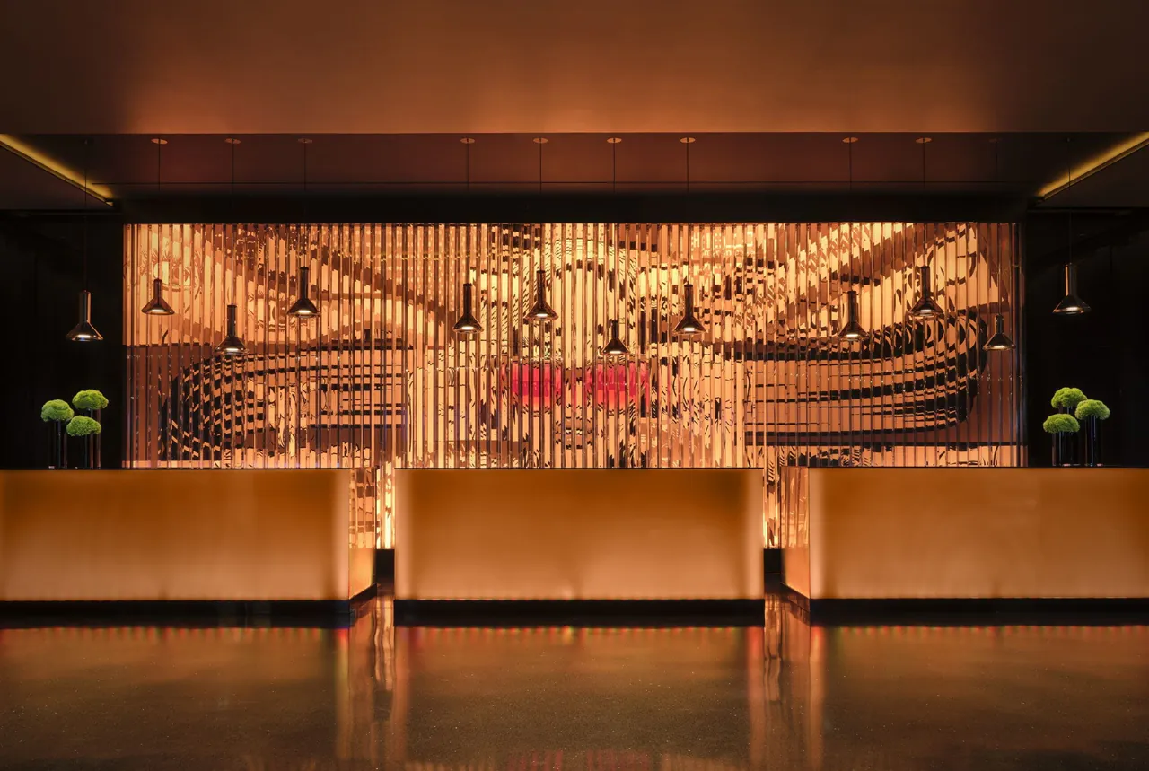 The reception desk set against a sculpted, warmly lit art wall.