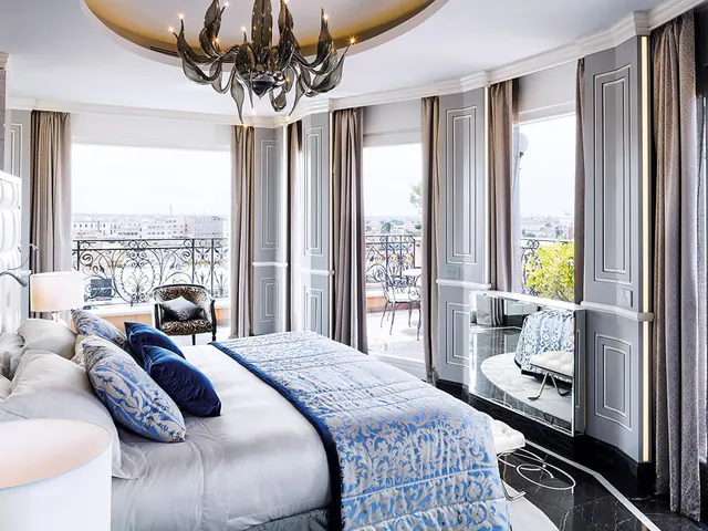 A bright bedroom with a curved wall of windows and a balcony overlooking Rome.