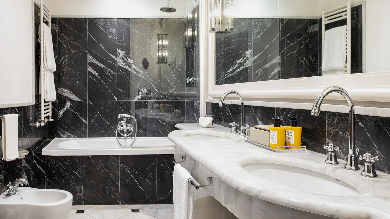A black and white marble bathroom with a bathtub and a double washbasin.
