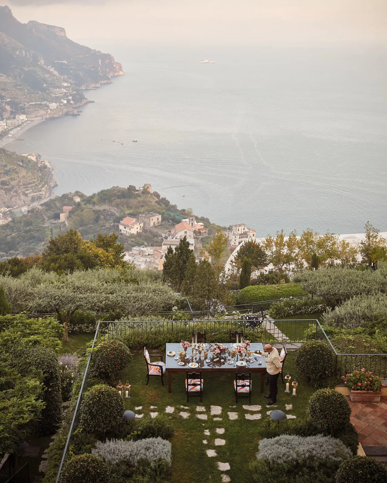 A table dressed with flowers and candles in the gardens above the coast.
