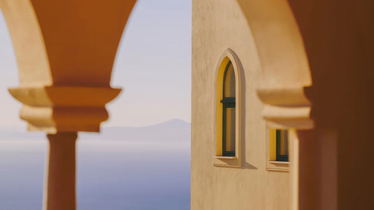 Pale stone arches frame the sea beside an arched window of the palace.