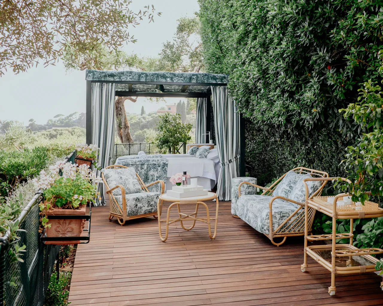 A shaded cabana with cushioned sofas on a wooden deck in the spa garden.