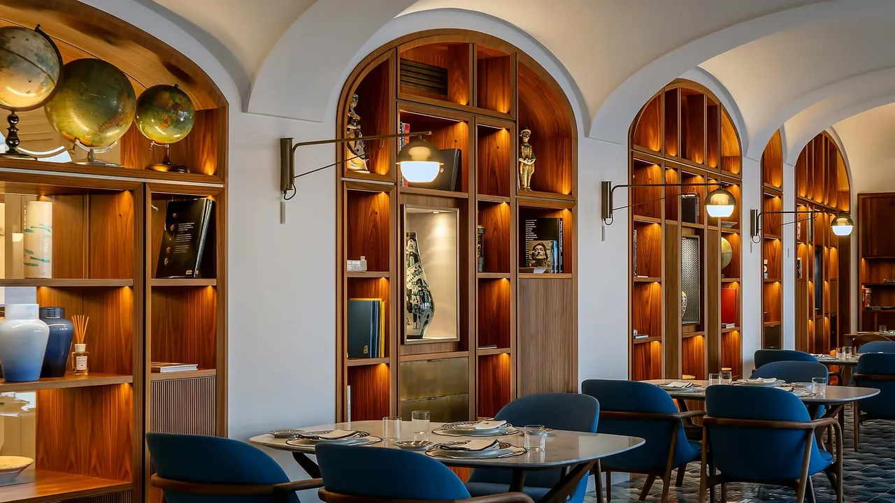 A dining room with arched walnut shelves, old globes and blue chairs.