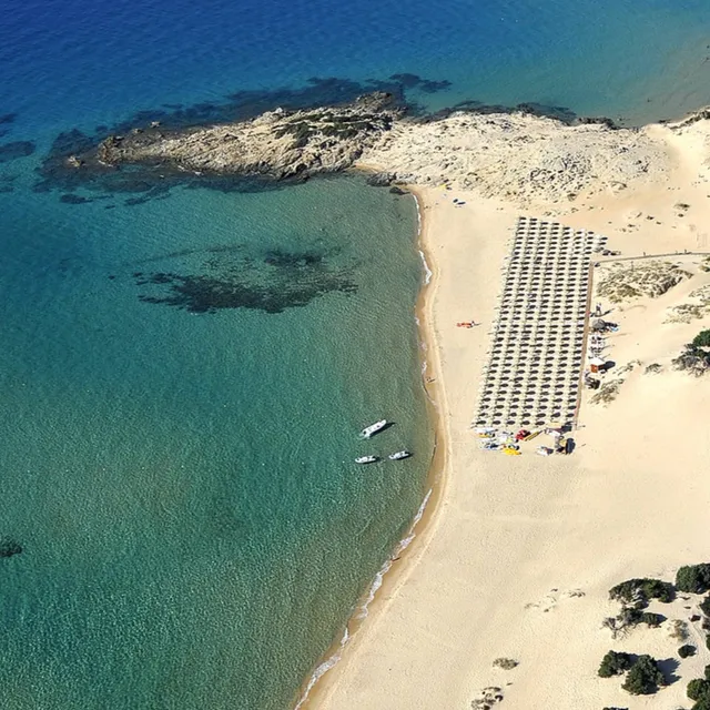 Aerial view of a sandy beach with rows of parasols and turquoise water at Chia Laguna Resort, Sardinia
