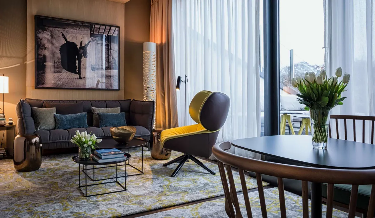 A suite living area with designer chairs and a dining table by the window.