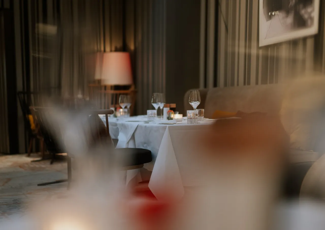 A softly lit restaurant table set with white linen and glassware.
