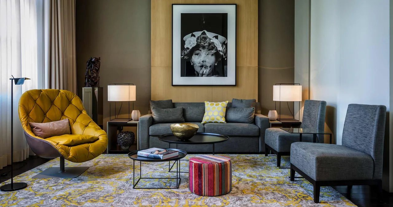A lounge corner in a suite with a yellow armchair and grey sofas.