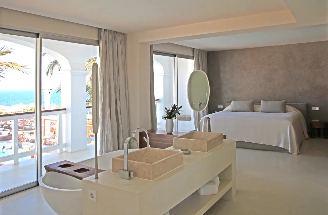Suite at Destino Five Ibiza with a stone basin, freestanding tub and a balcony facing the sea