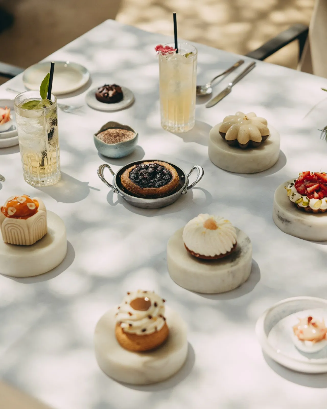 Small pastries and iced drinks laid out for an afternoon tea.