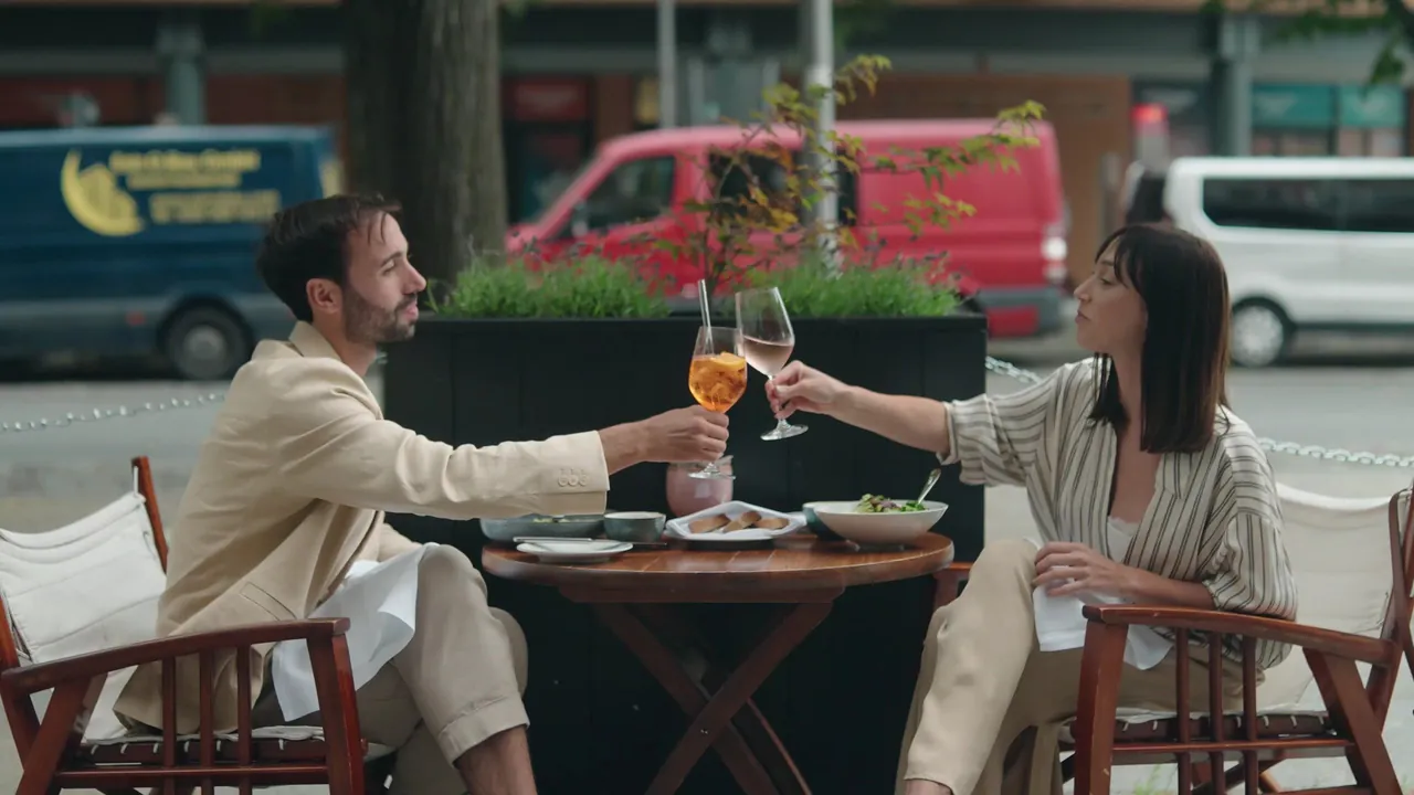 A couple raising their glasses at a table on the outdoor terrace.