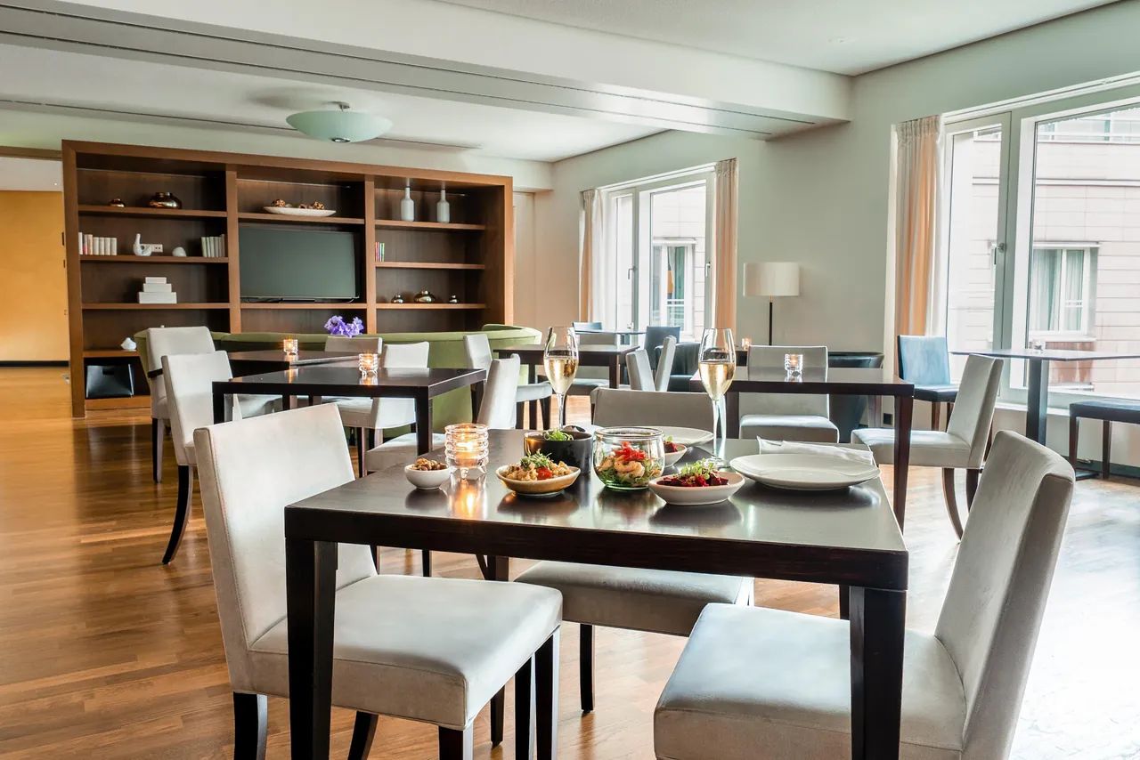 Restaurant with white chairs, dark tables and tall bookshelves.