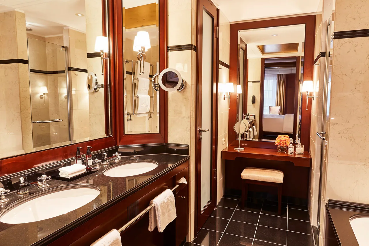 A marble bathroom with double sinks and a vanity mirror.