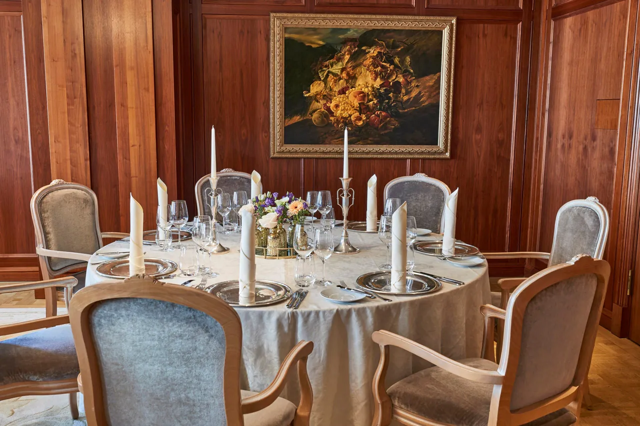 A wood panelled private dining room with a set round table.