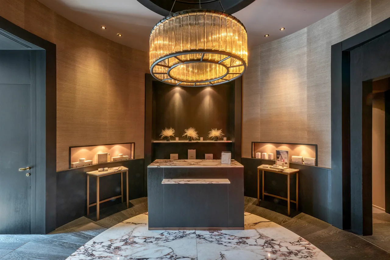 The entrance hall with a round crystal chandelier, dark wood walls and display cases.