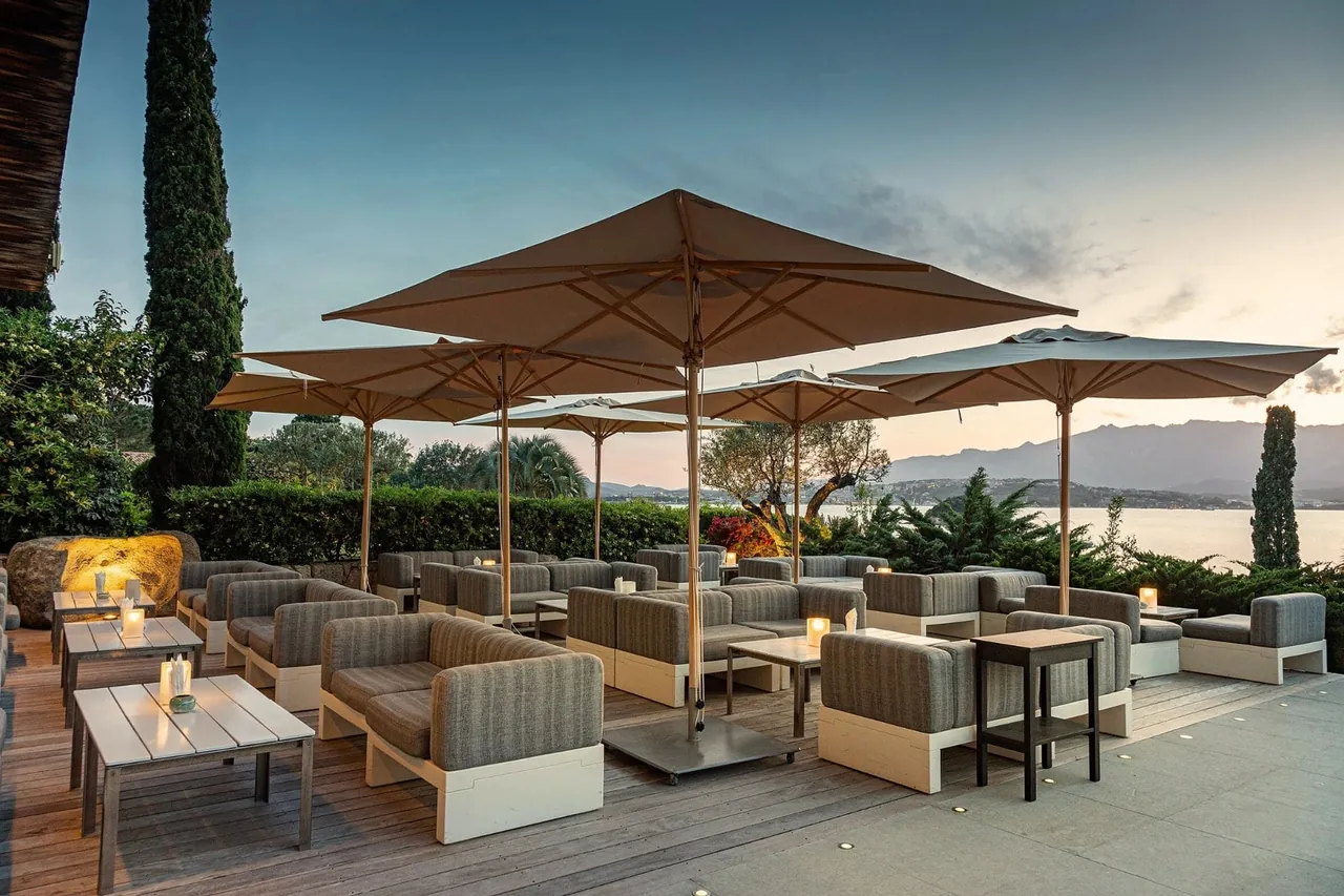 The bar terrace under large parasols in the evening light, looking out to the gulf.