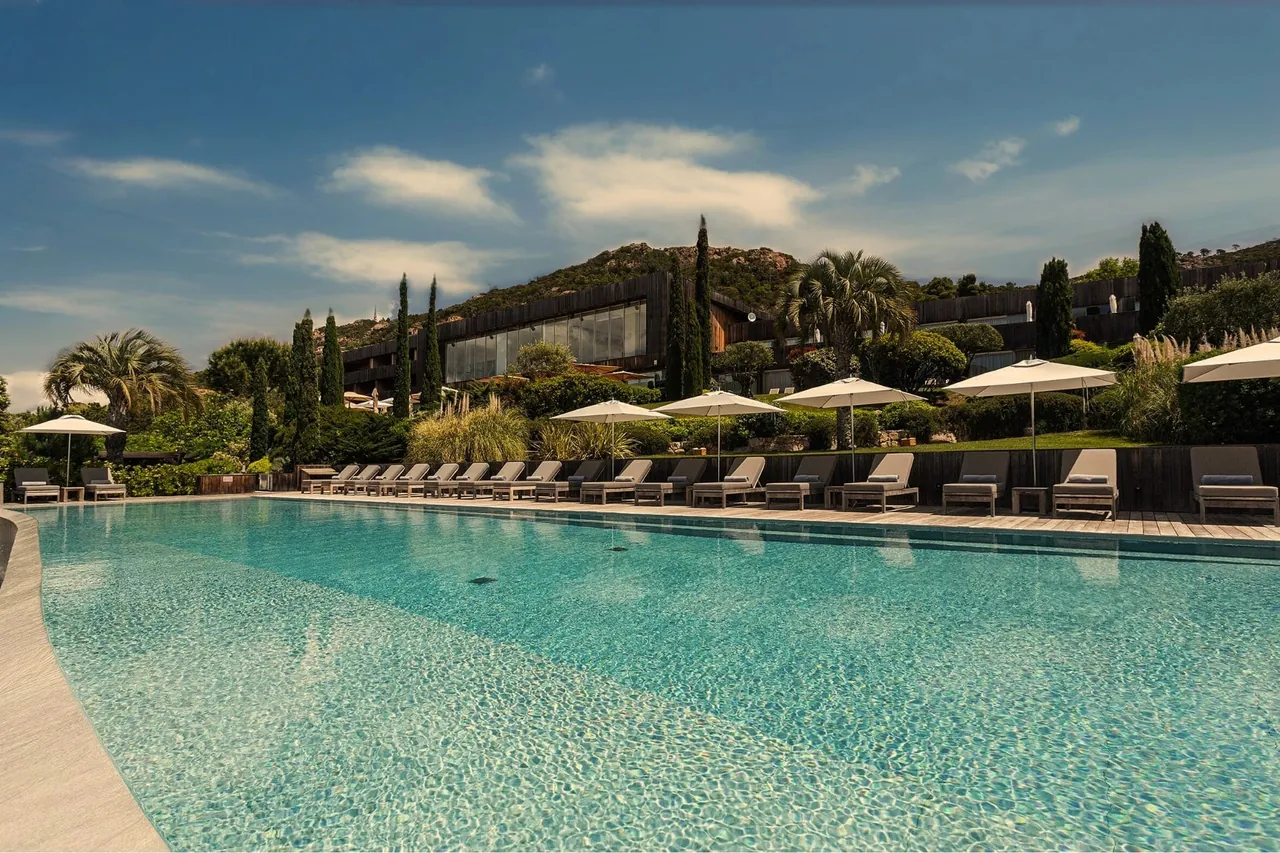 The heated pool with sun loungers and parasols, and the hotel on the hillside behind.