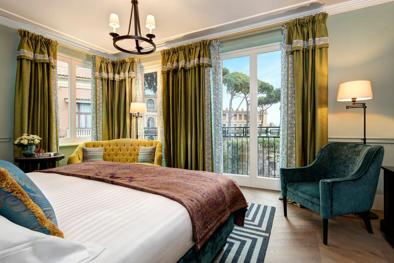 A guest room with olive curtains and French windows facing Roman rooftops.