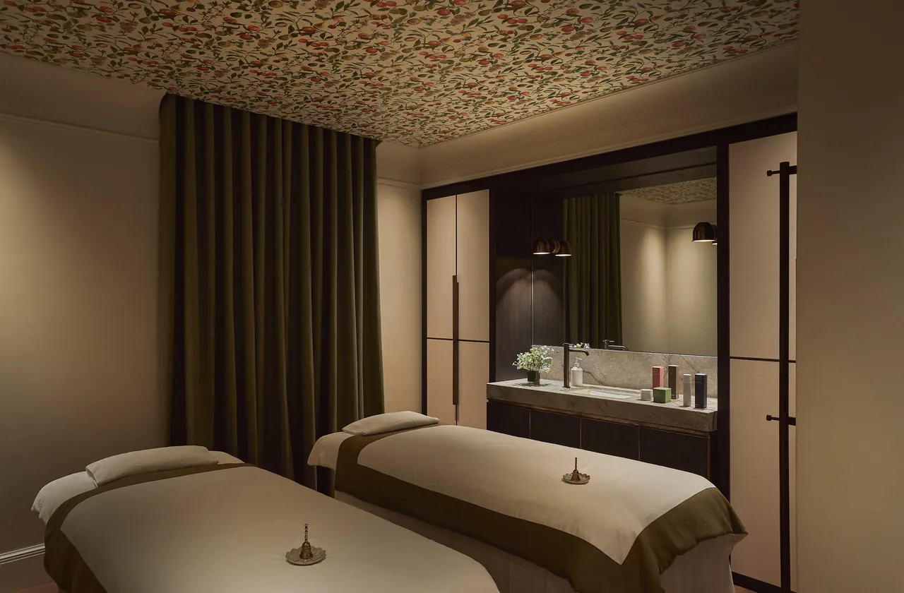 A softly lit spa treatment room with two massage beds.