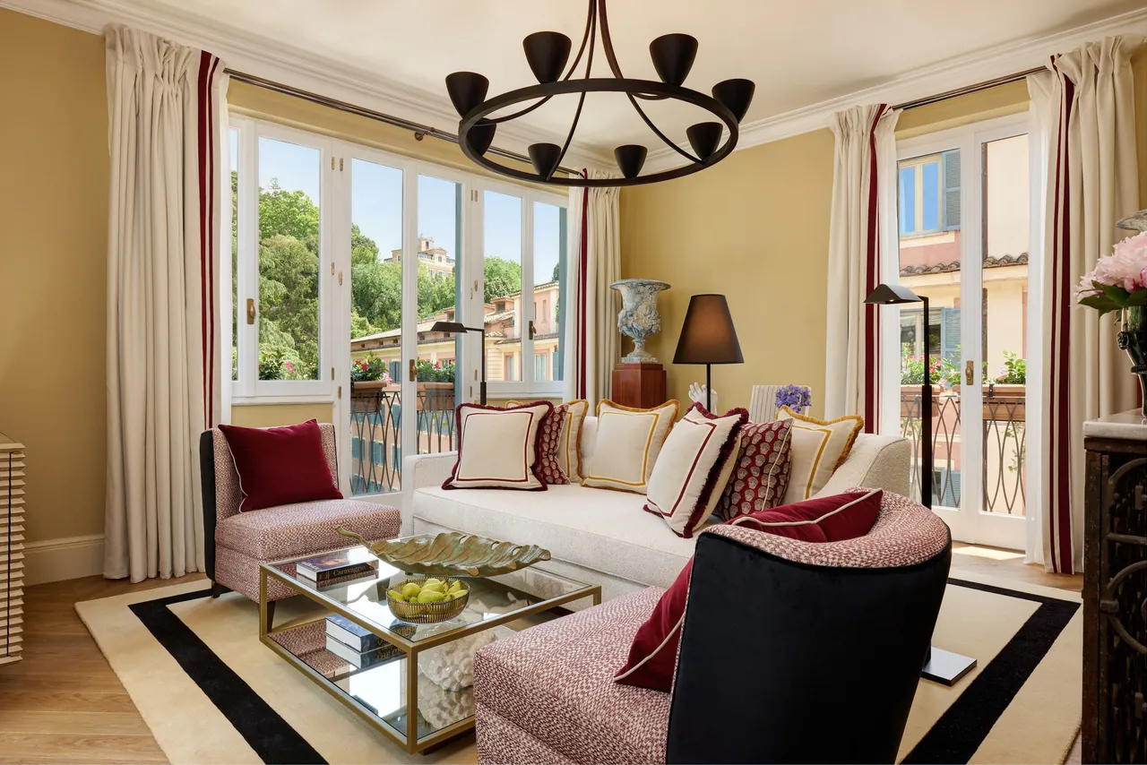 A bright suite living room with a chandelier and tall windows.