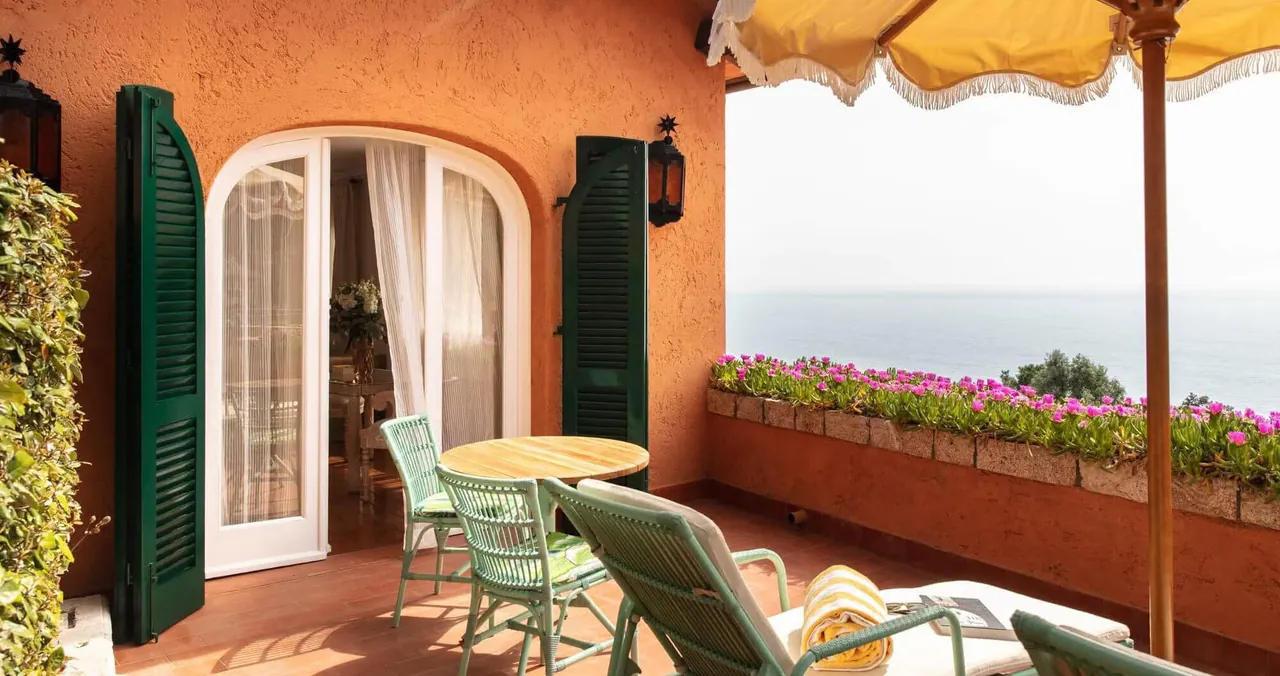 A suite terrace with sun loungers, flowers and a view of the sea.