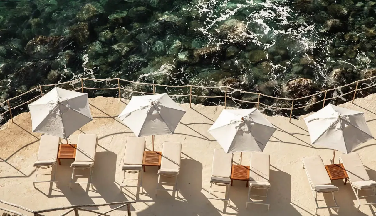 White parasols and sun loungers on the rocky sea terrace.