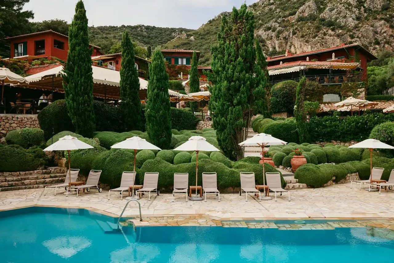 The swimming pool lined with white parasols below the hotel's terracotta villas.