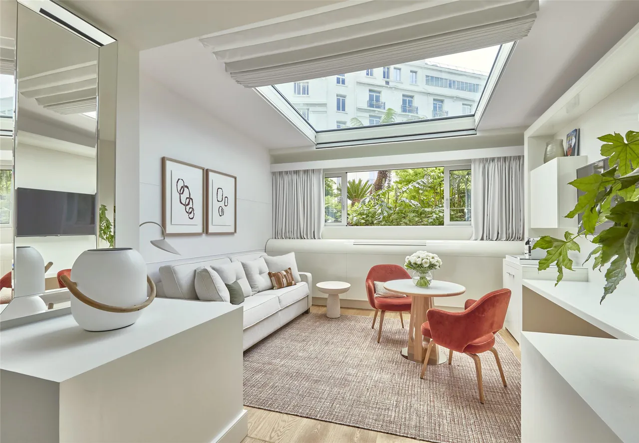 A bright suite living room with white sofas under a skylight.