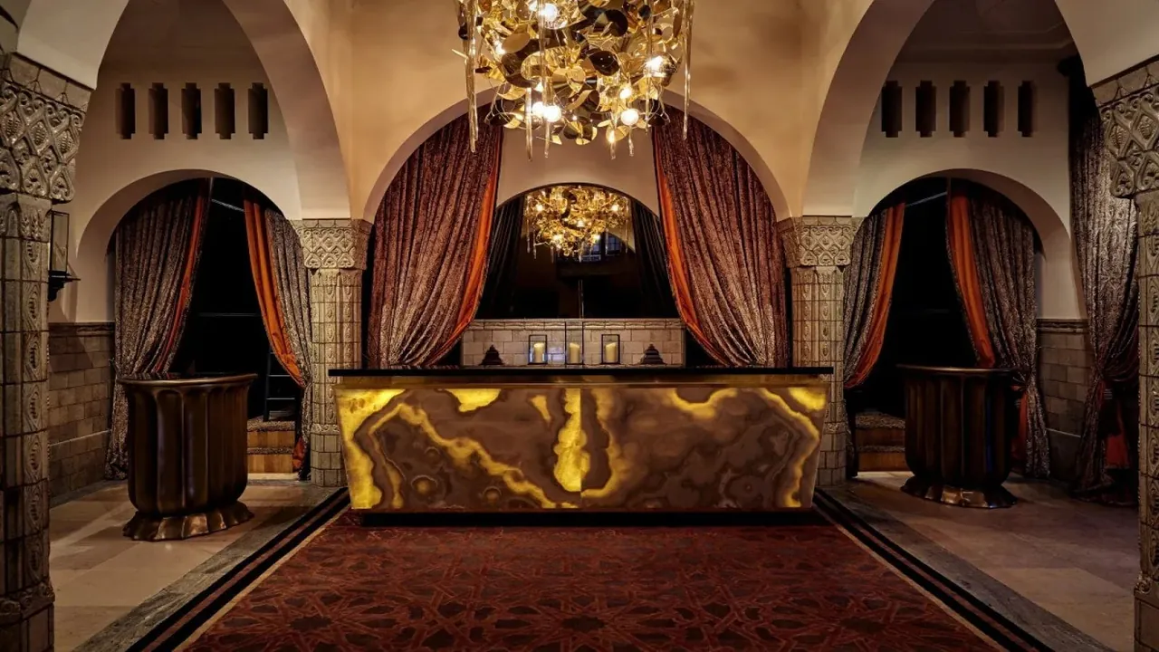 The reception desk glows beneath a crystal chandelier and heavy drapes.