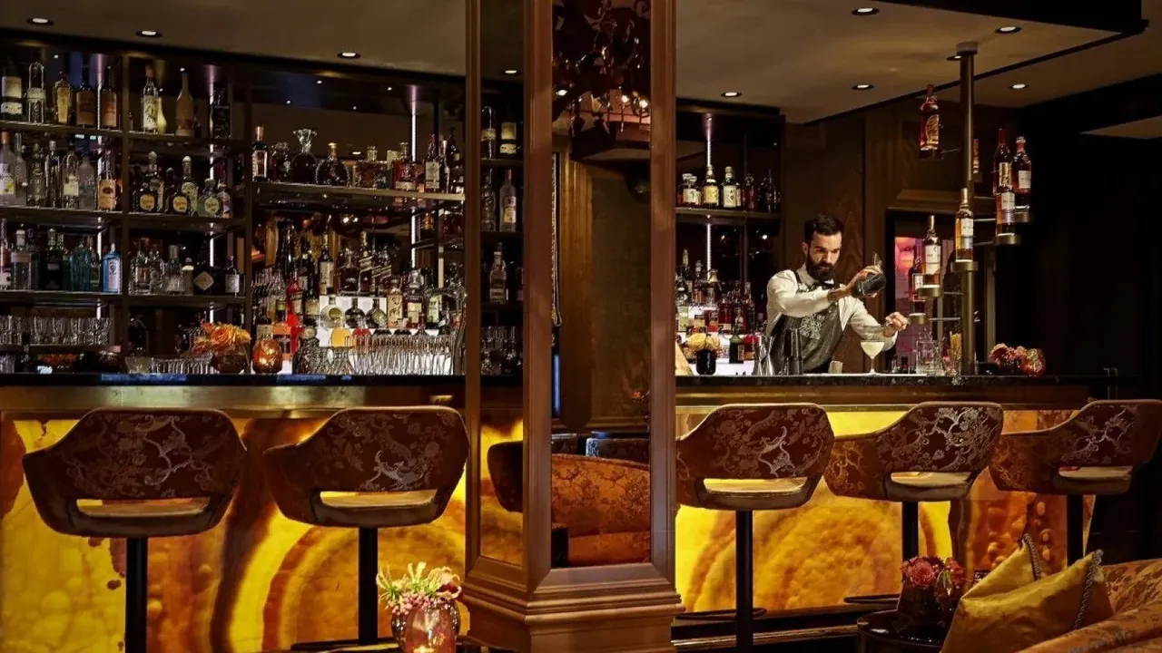 A bartender works behind the glowing bar counter.