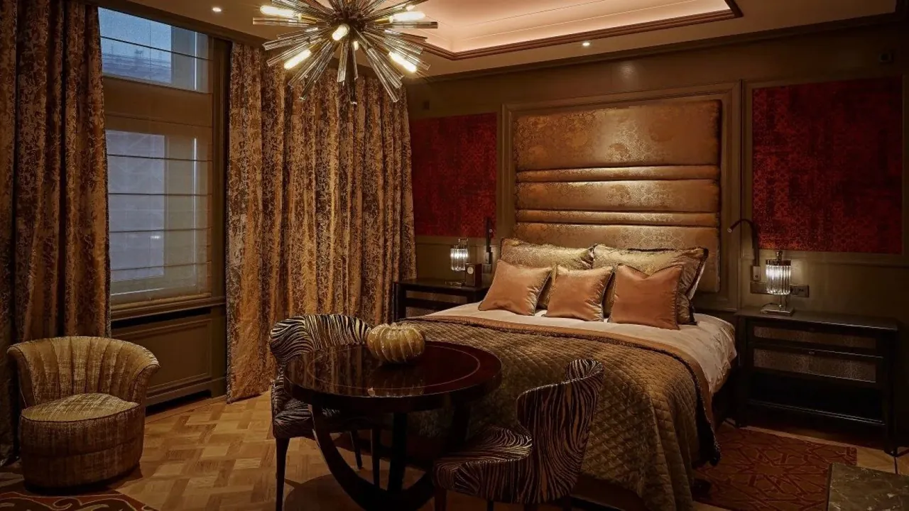 A junior suite bedroom with a padded headboard and a starburst chandelier.