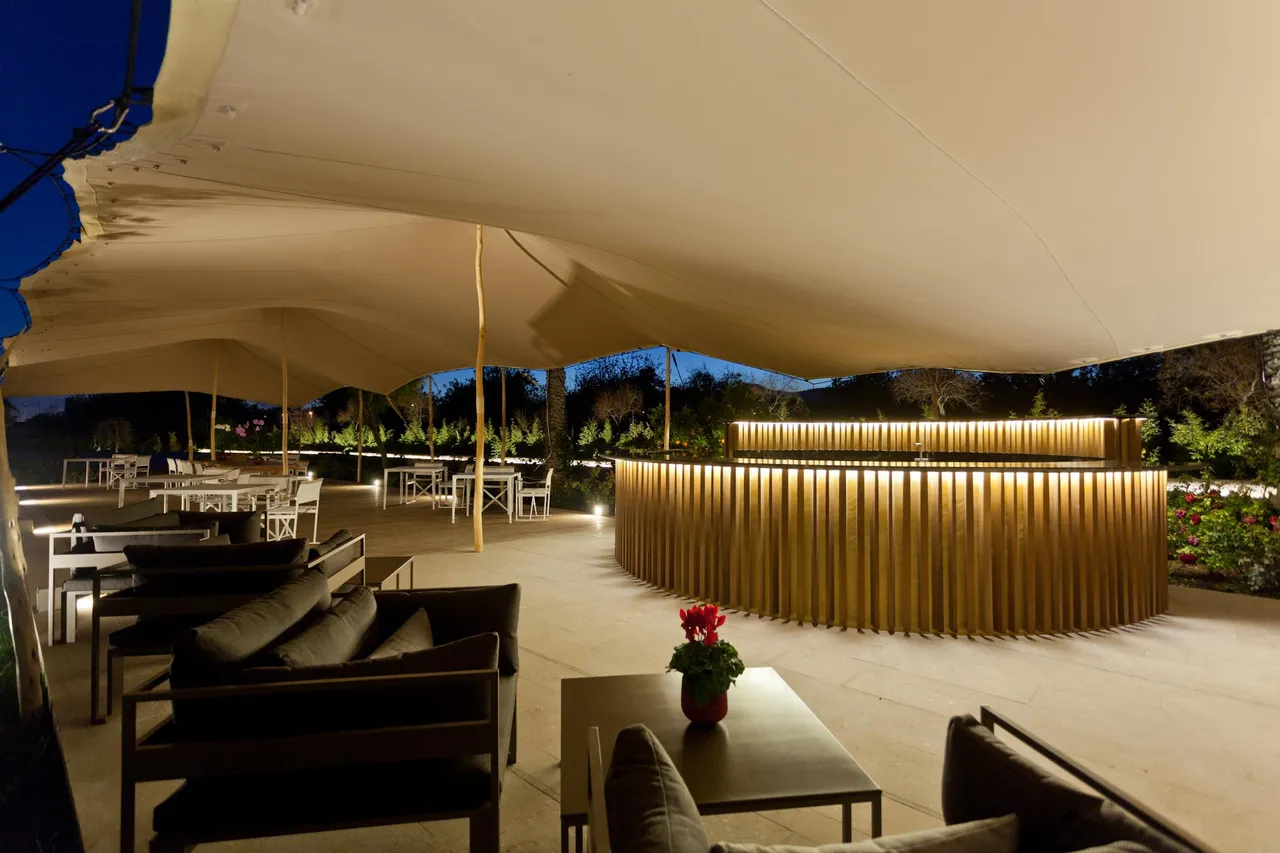 Outdoor bar at Hotel Xereca, Ibiza, at night under a canvas canopy with a lit timber counter