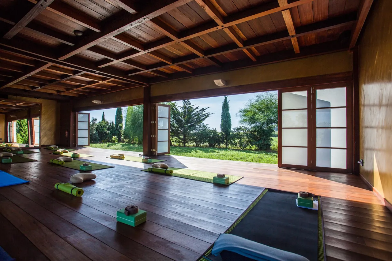 Yoga pavilion at Hotel Xereca, Ibiza, with wooden floors, laid-out mats and sliding doors open to the garden
