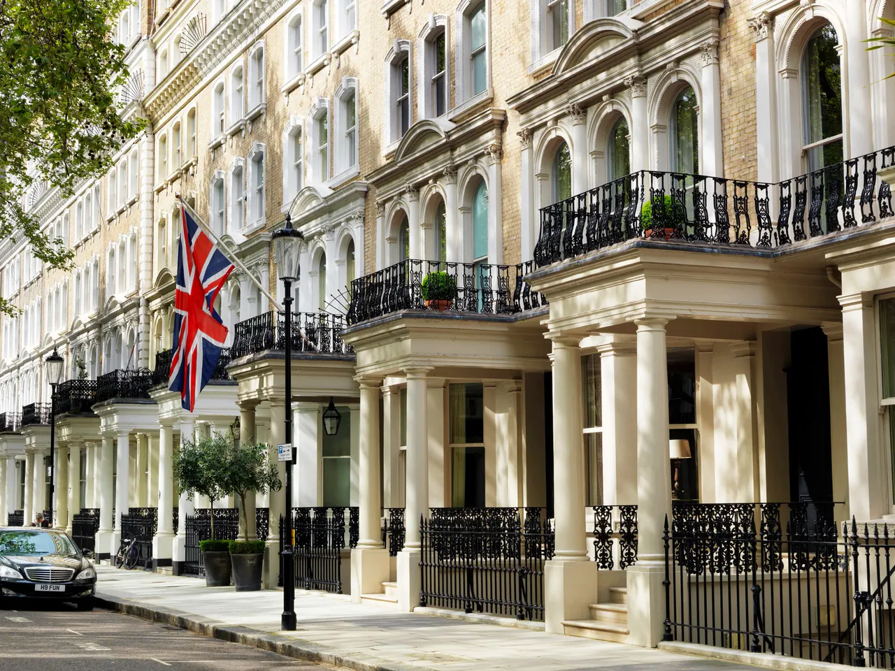 Cream stucco townhouse facade of Knightsbridge Hotel with a Union Jack flag.