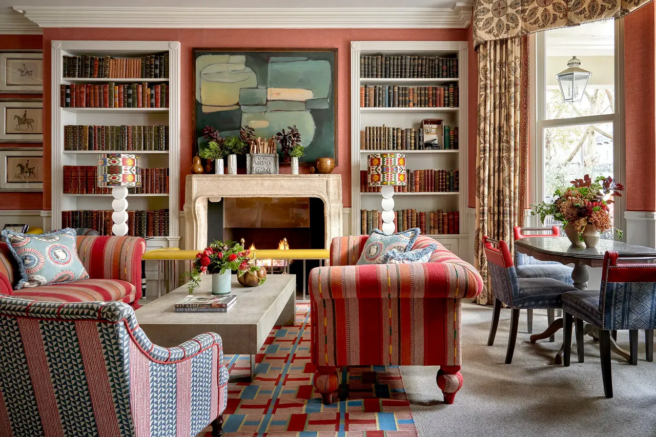 Library lounge with striped armchairs, full bookshelves and a fireplace.