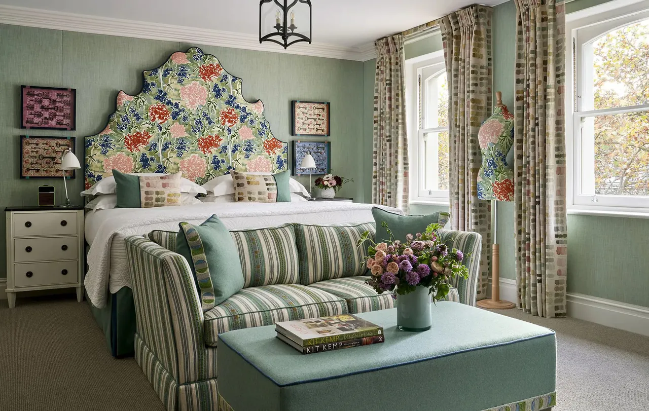 Junior suite with a tall floral headboard and a sage green sofa.