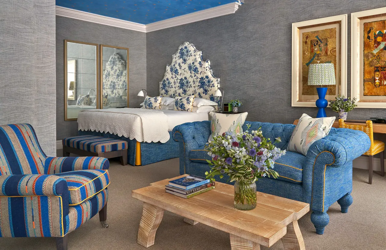 Knightsbridge Suite bedroom with a blue sofa and a floral headboard.