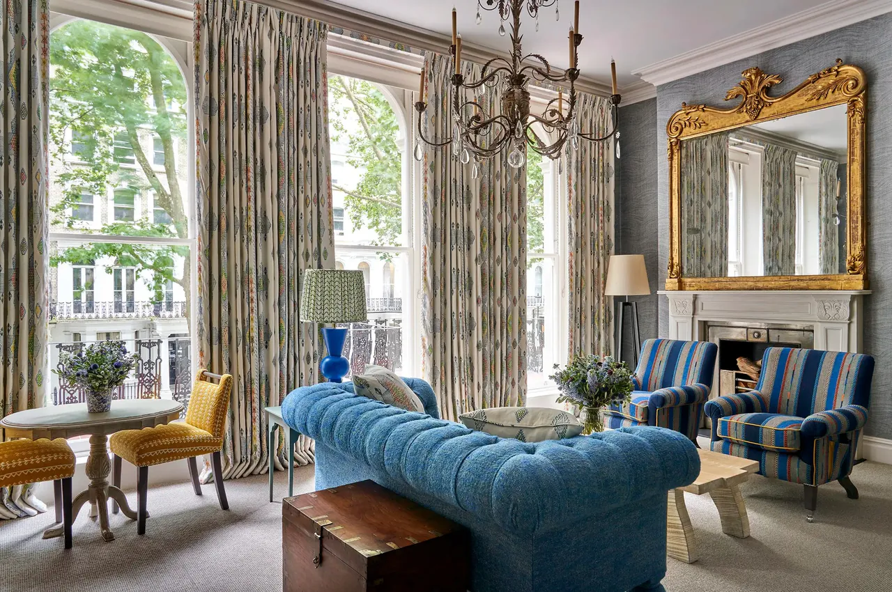 Sitting area of the Knightsbridge Suite with a blue chesterfield and a gilt mirror.
