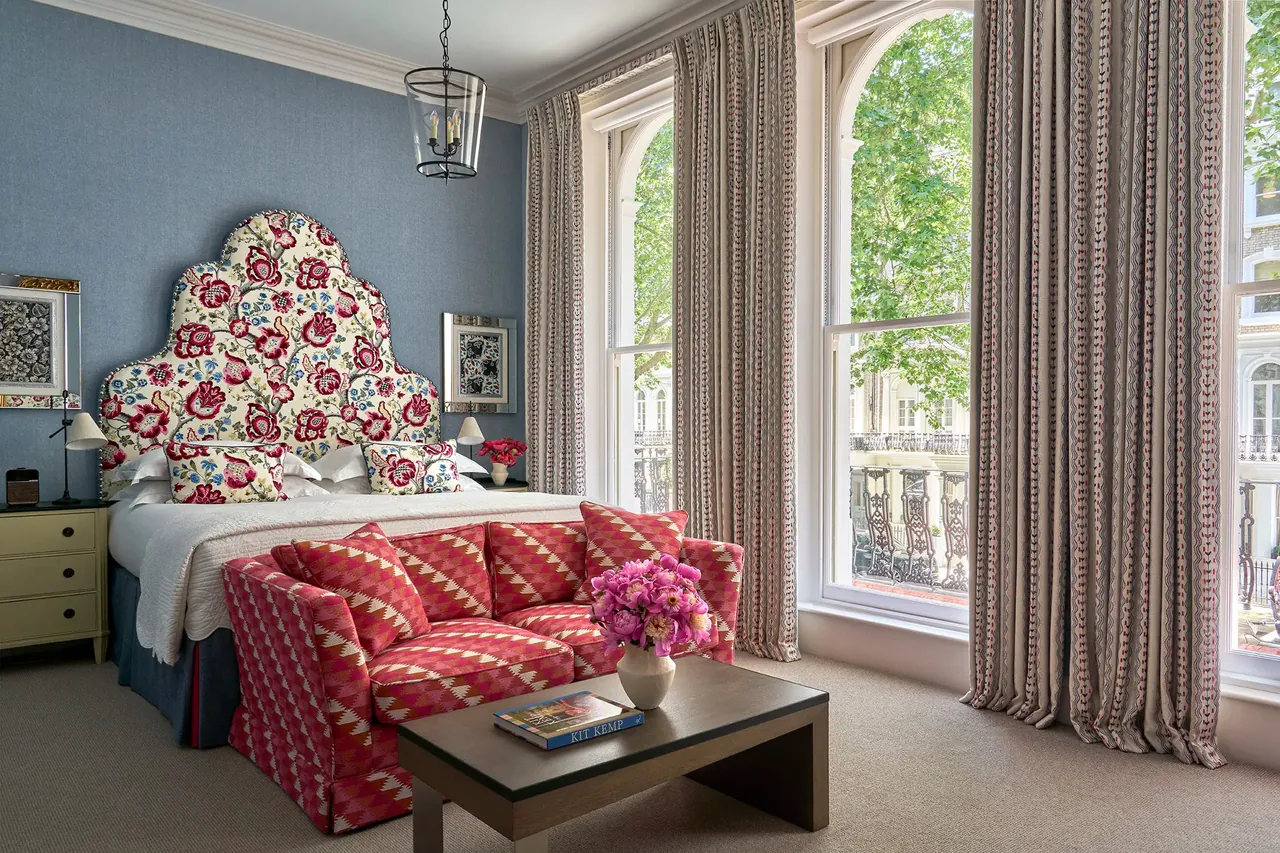 Junior suite bedroom with a red patterned headboard and tall sash windows.