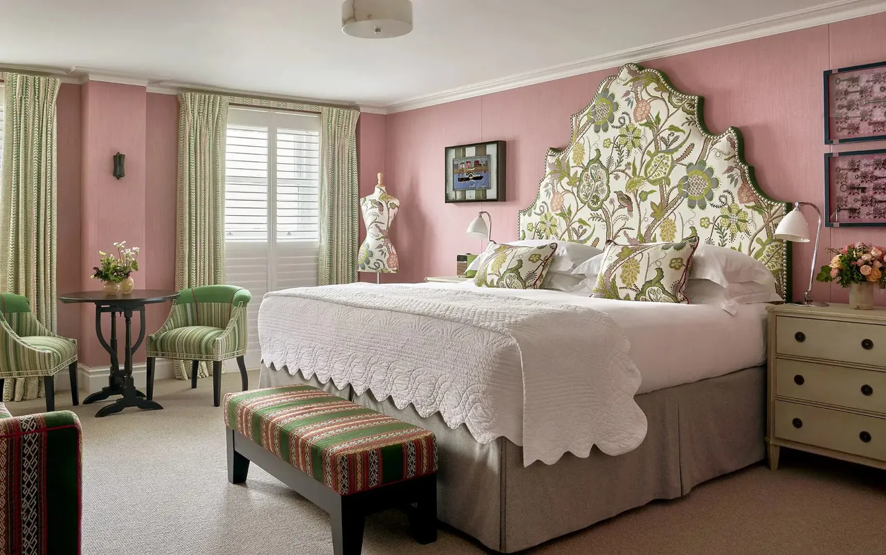 Deluxe Room with pink walls and a green botanical headboard.