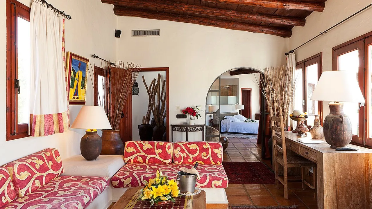 Living room at Las Brisas with red patterned sofas, terracotta floors, wooden beams and an arched doorway