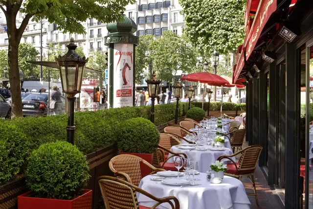 Street terrace at Le Fouquet's Barriere, Paris, with white tablecloths, wicker chairs and red parasols
