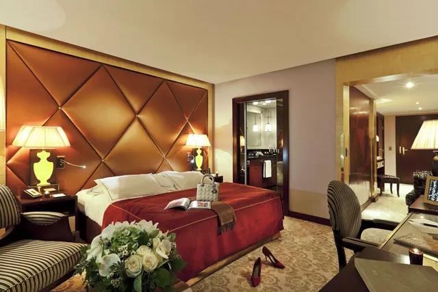 Guest room at Le Fouquet's Barriere, Paris, with a quilted leather headboard, red bedspread and gold lamps