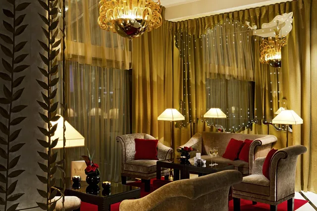 Lounge at Le Fouquet's Barriere, Paris, with gold drapes, velvet armchairs, red cushions and table lamps