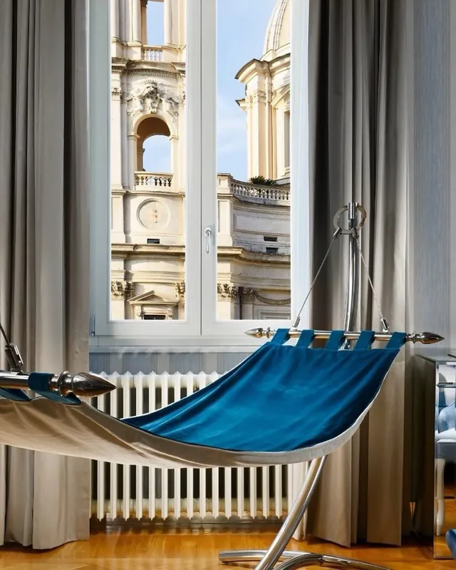 A blue hammock beside a tall window looking onto the piazza.